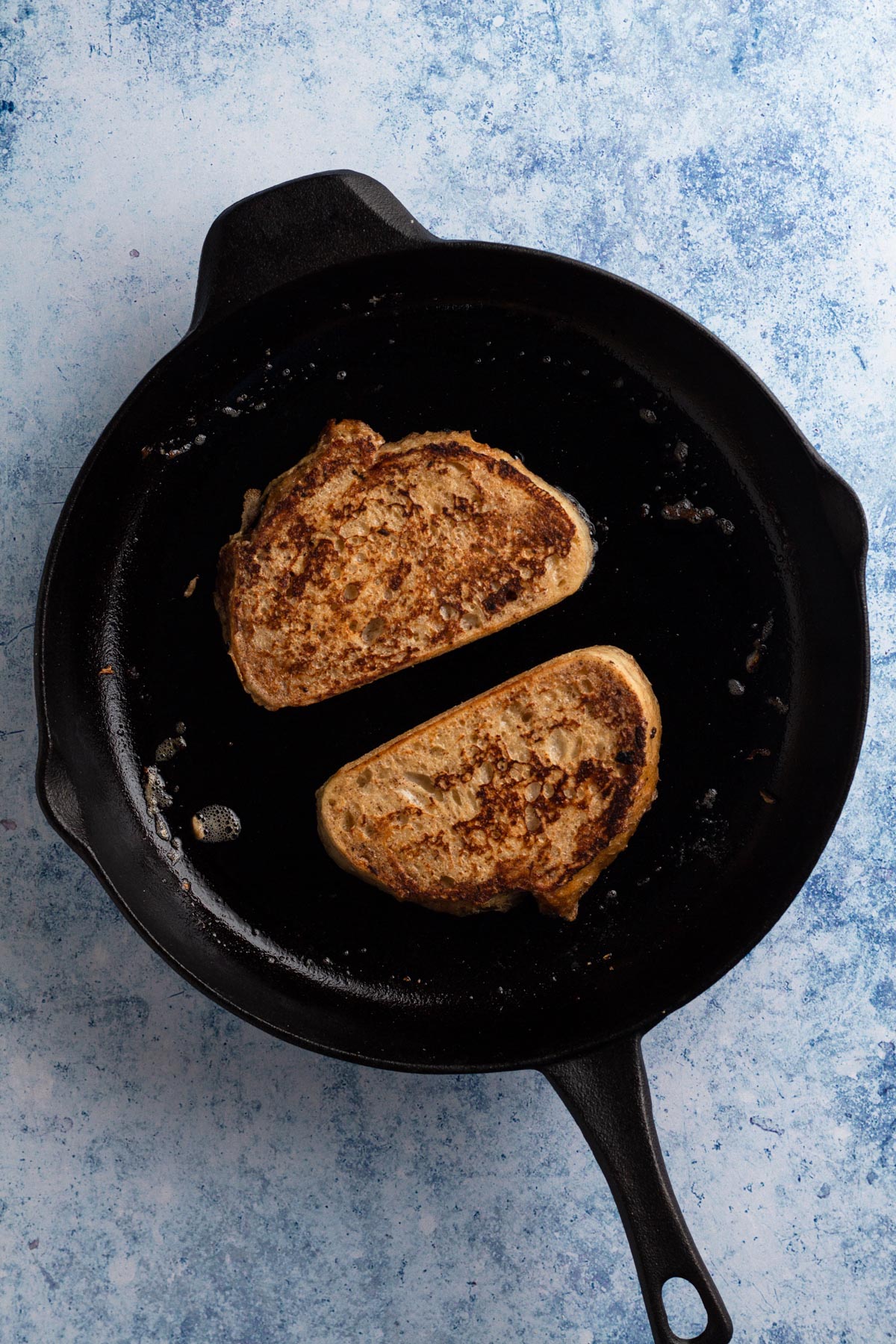 Golden brown slices of French toast in a cast iron skillet.