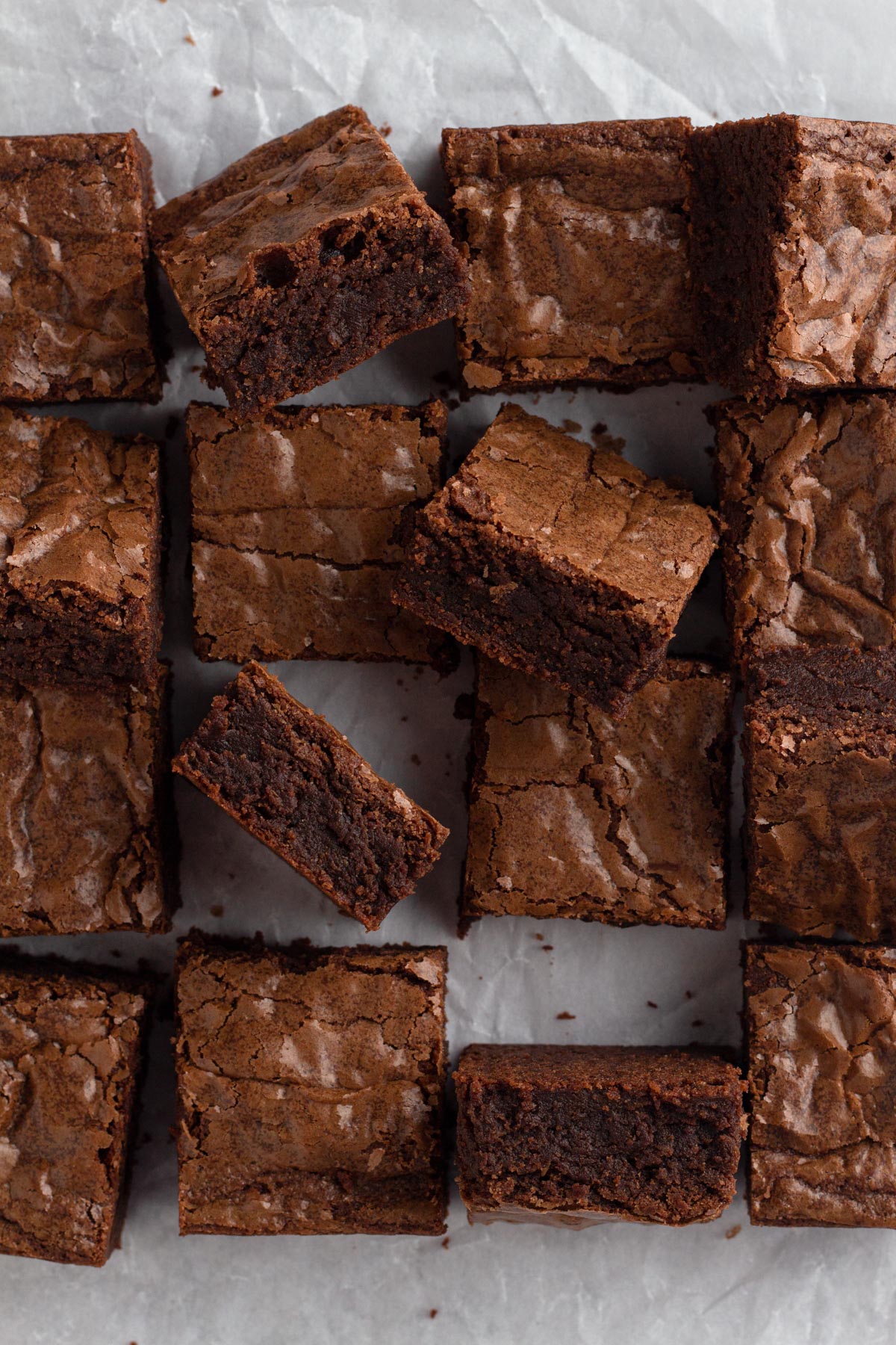 Sliced brownies scattered on a crinkled piece of parchment paper.