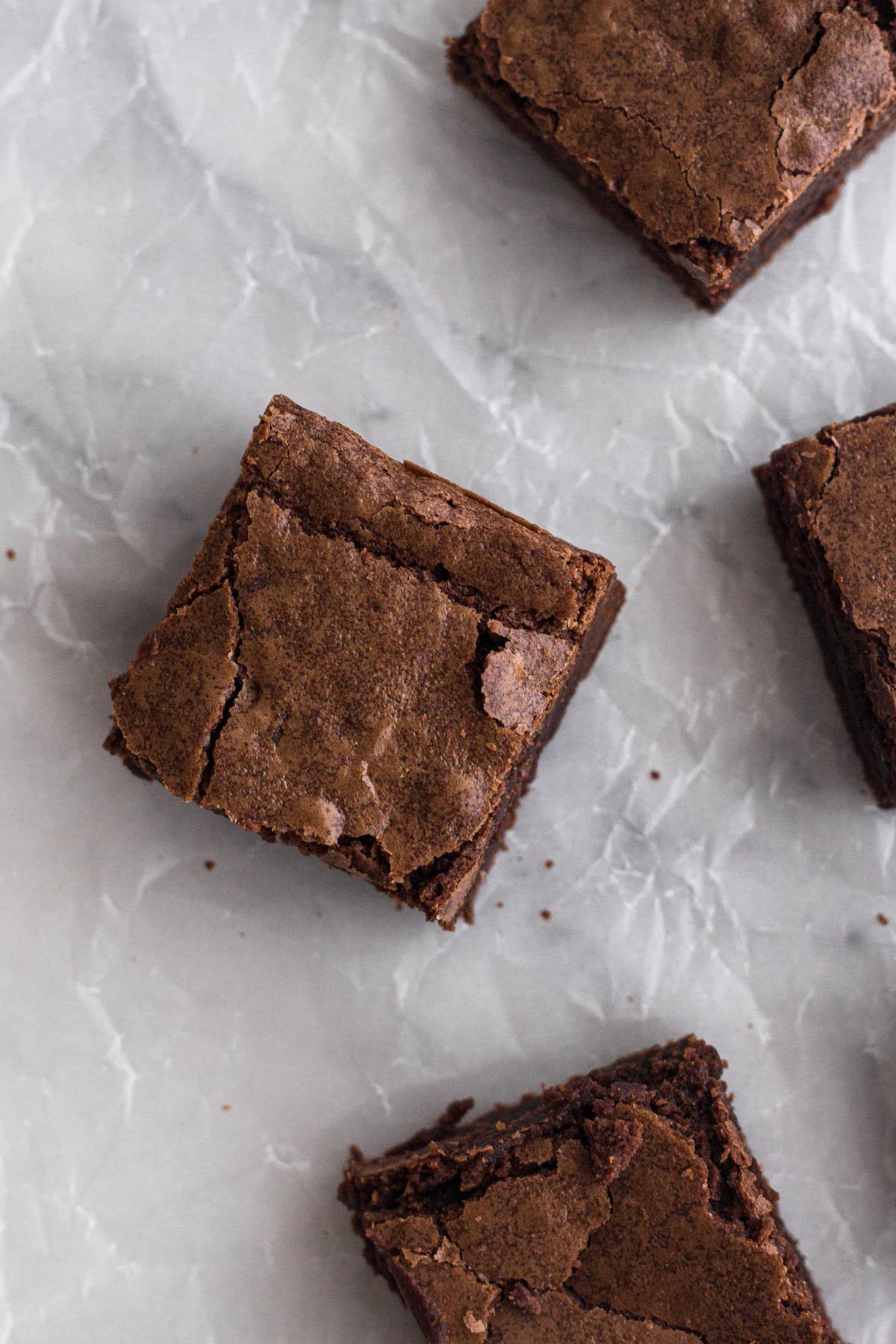 Overhead view of sliced brownies on crinkled parchment paper.