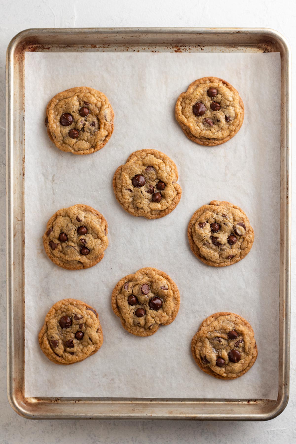 Baked cookies with extra chocolate chips pressed into the tops on a baking sheet.