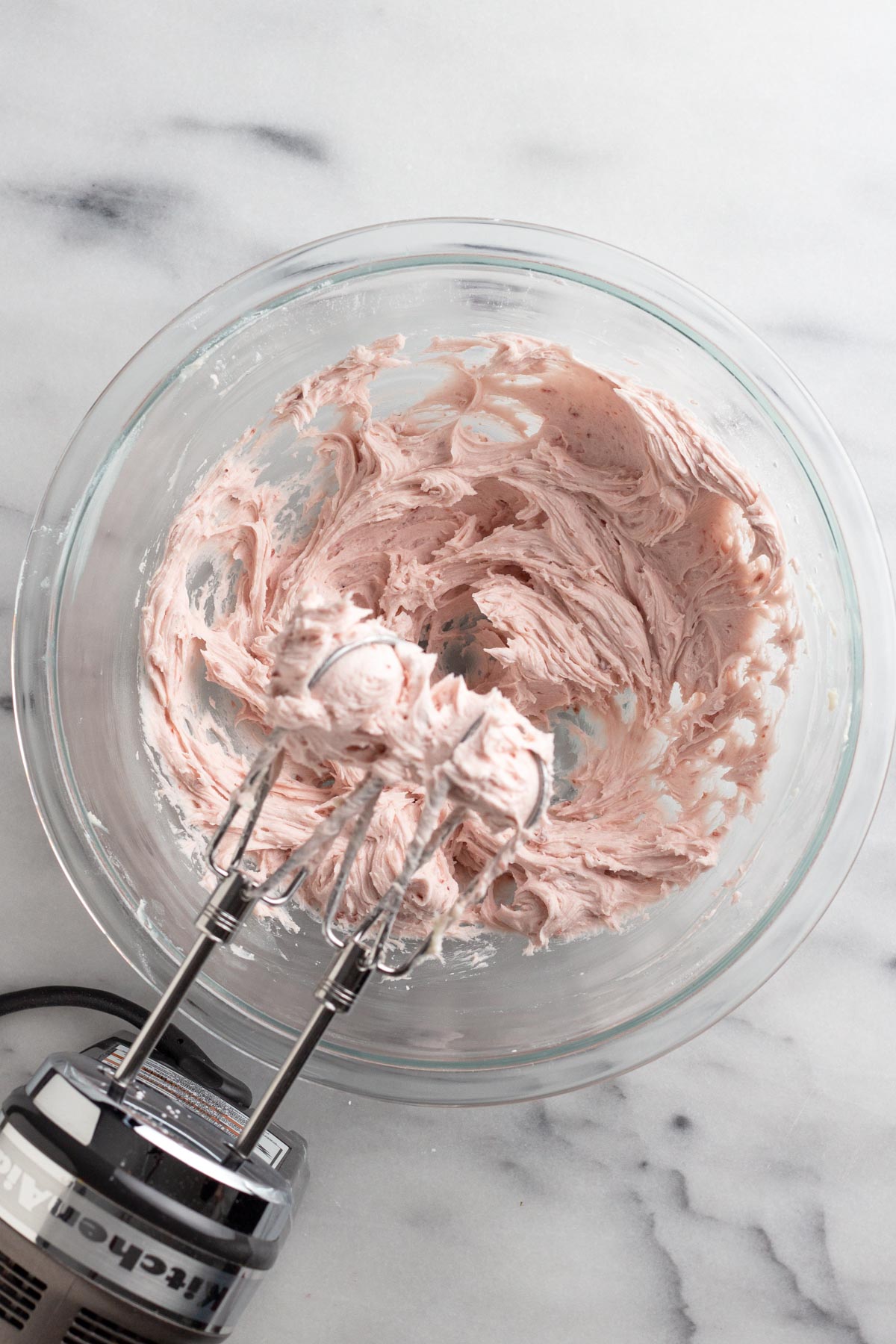 Pink raspberry butter cream frosting in a glass bowl.