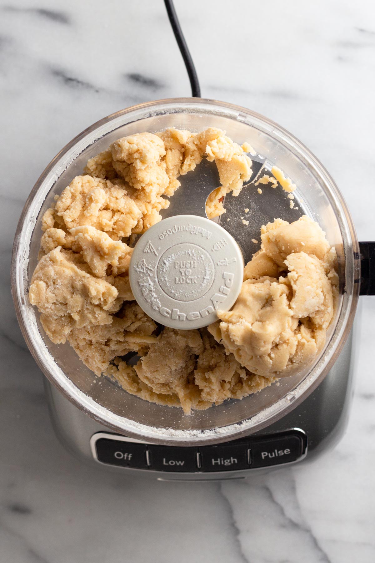 Cookie dough in the bowl of a food processor.
