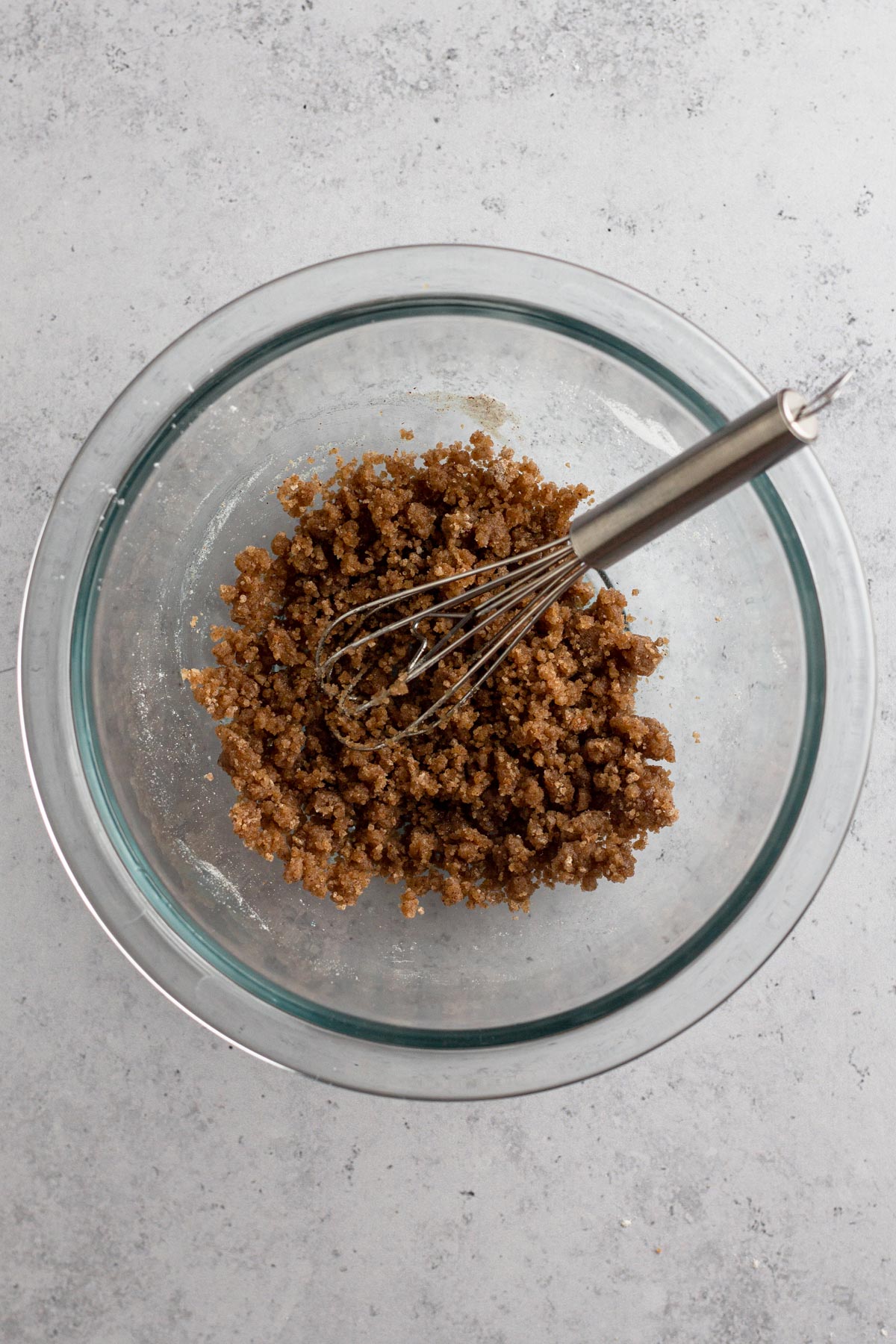 Overhead view of unbaked streusel in a glass bowl.