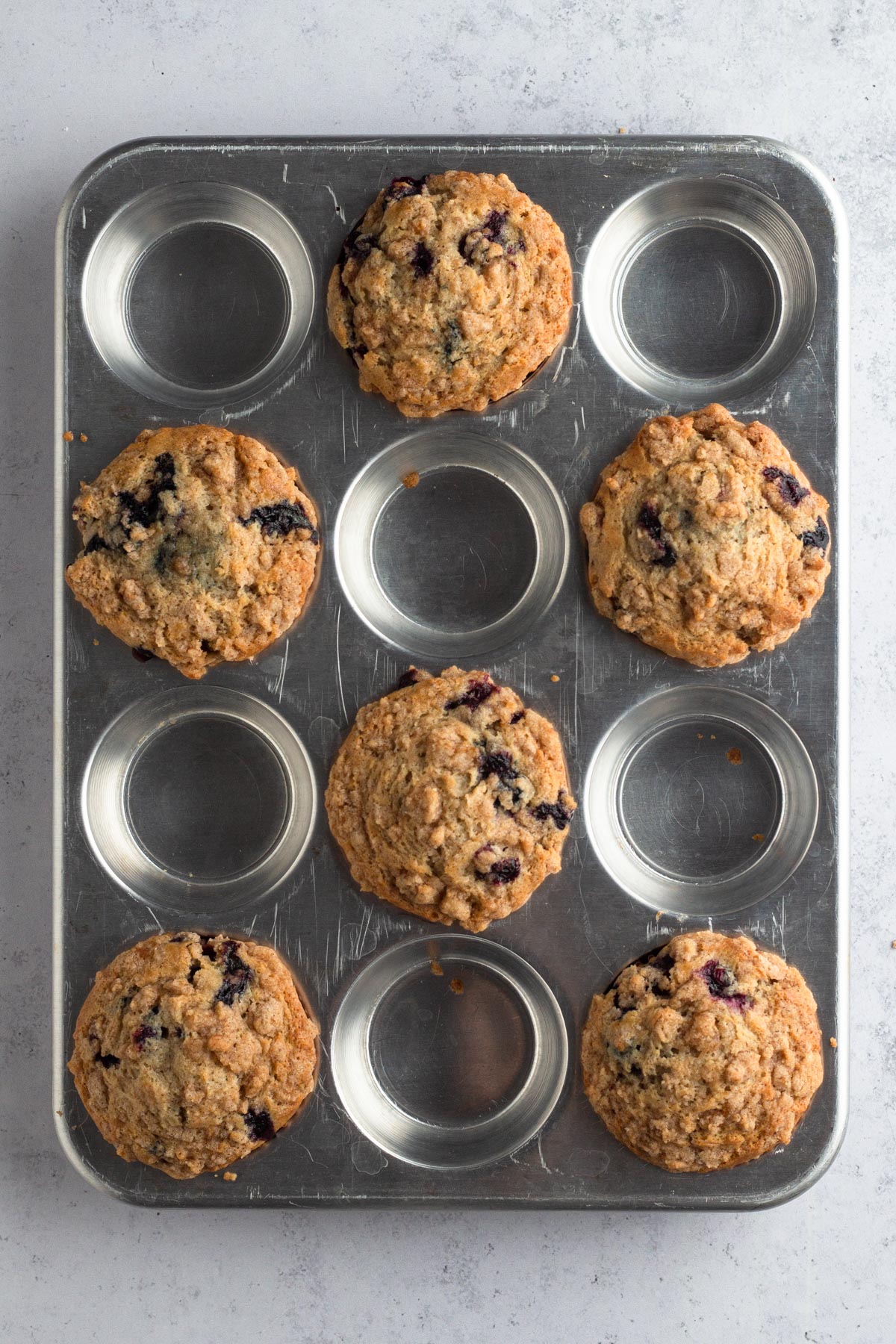 Six baked muffins in a metal muffin pan.