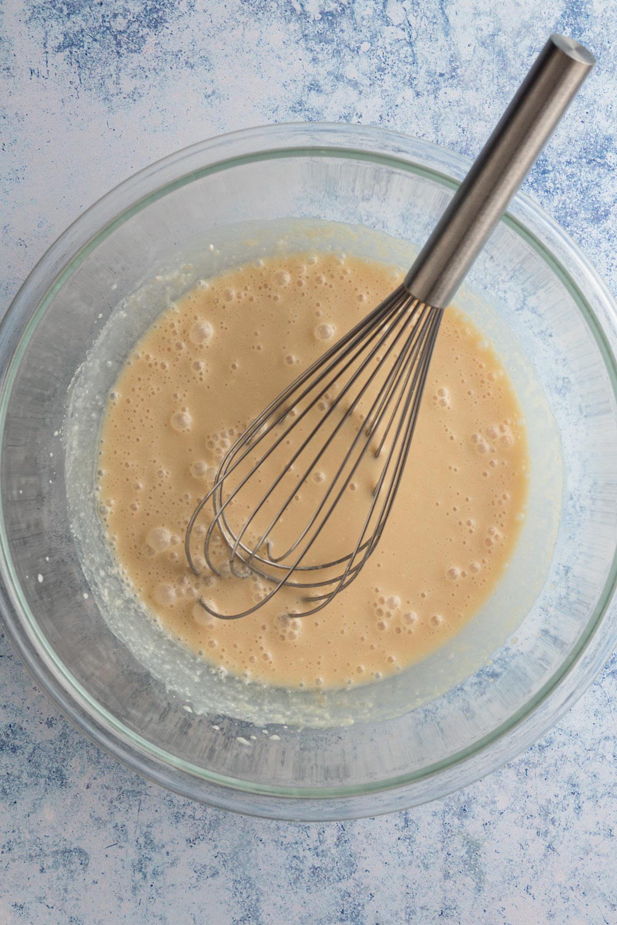 Overhead view of wet ingredients in a glass bowl.