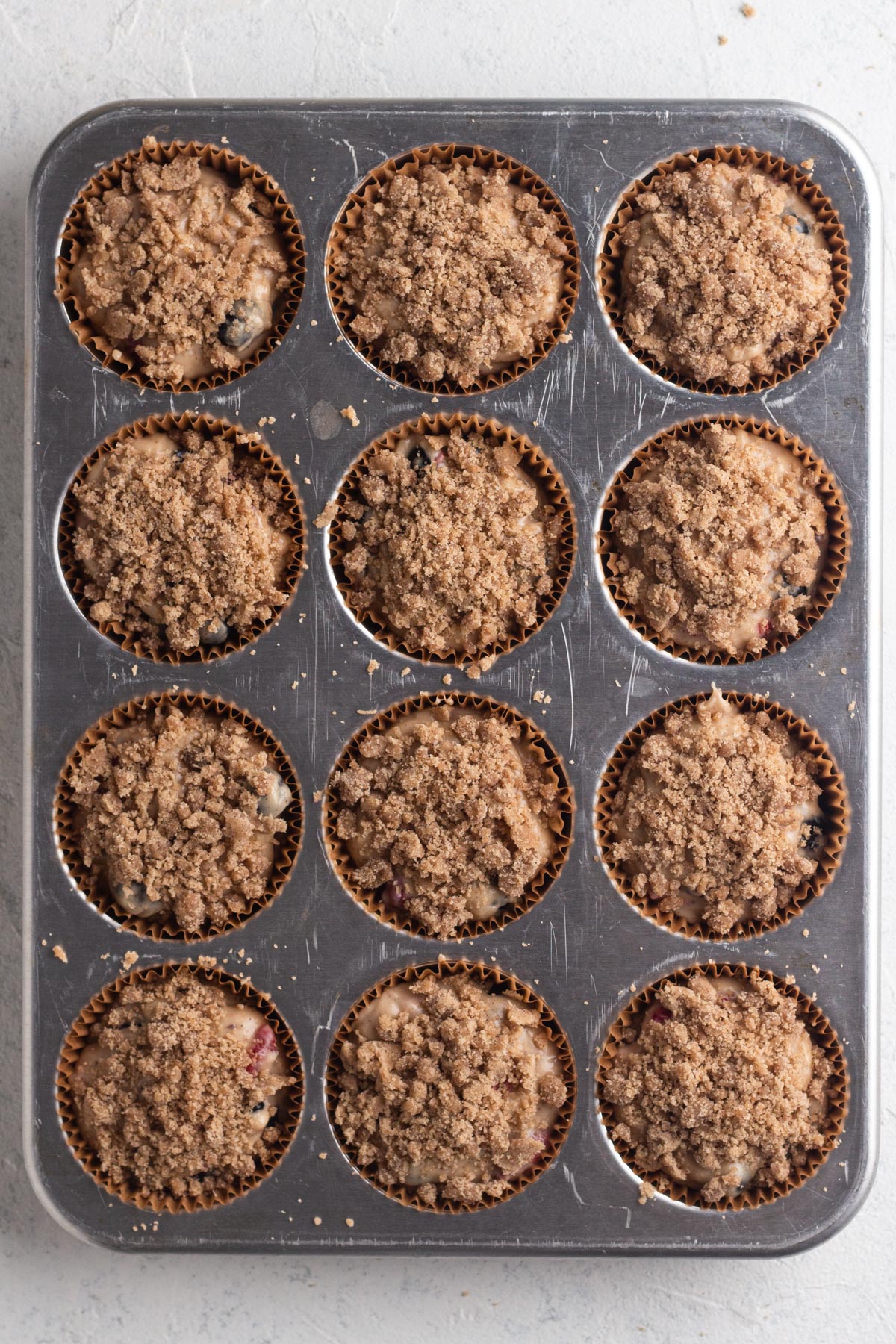 Muffin batter topped with streusel in a muffin pan.