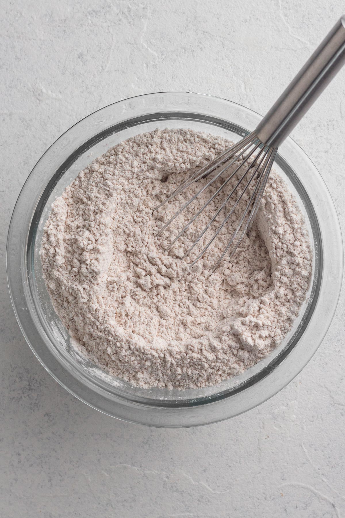 Dry ingredients whisked together in a glass bowl.