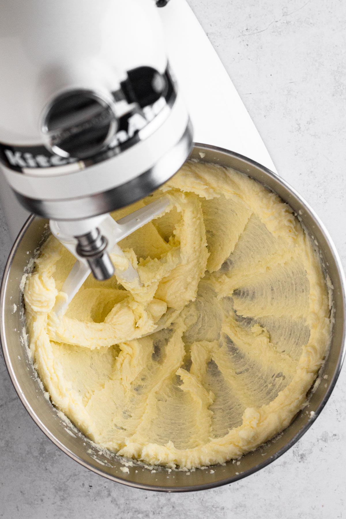 Creamed butter and sugar in the bowl of a white stand mixer with the paddle attachment.