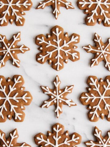 Overhead view of iced gingerbread cookies on a white marble surface.