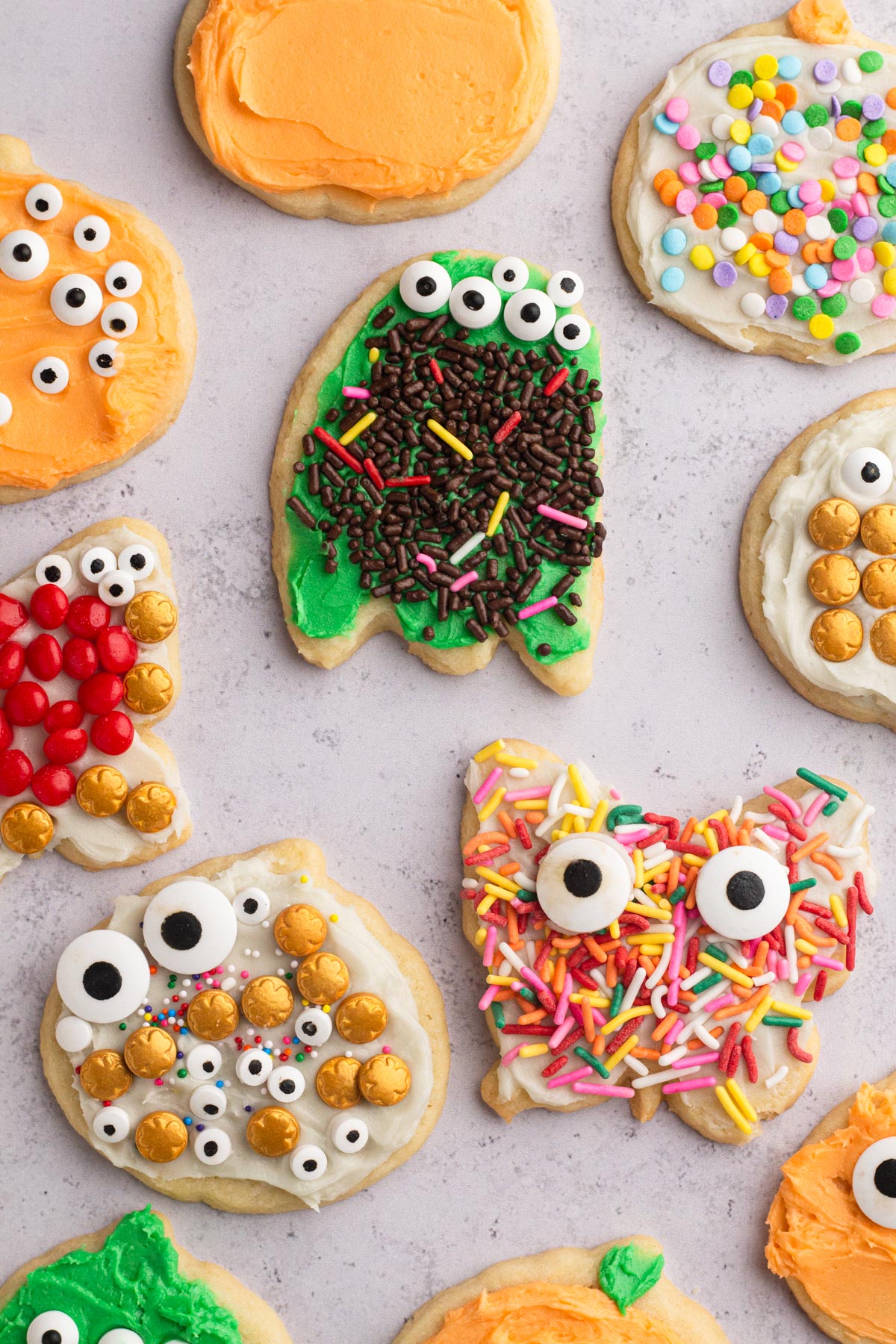 Halloween cut-out sugar cookies decorated by children using buttercream frosting and colorful assorted sprinkles.