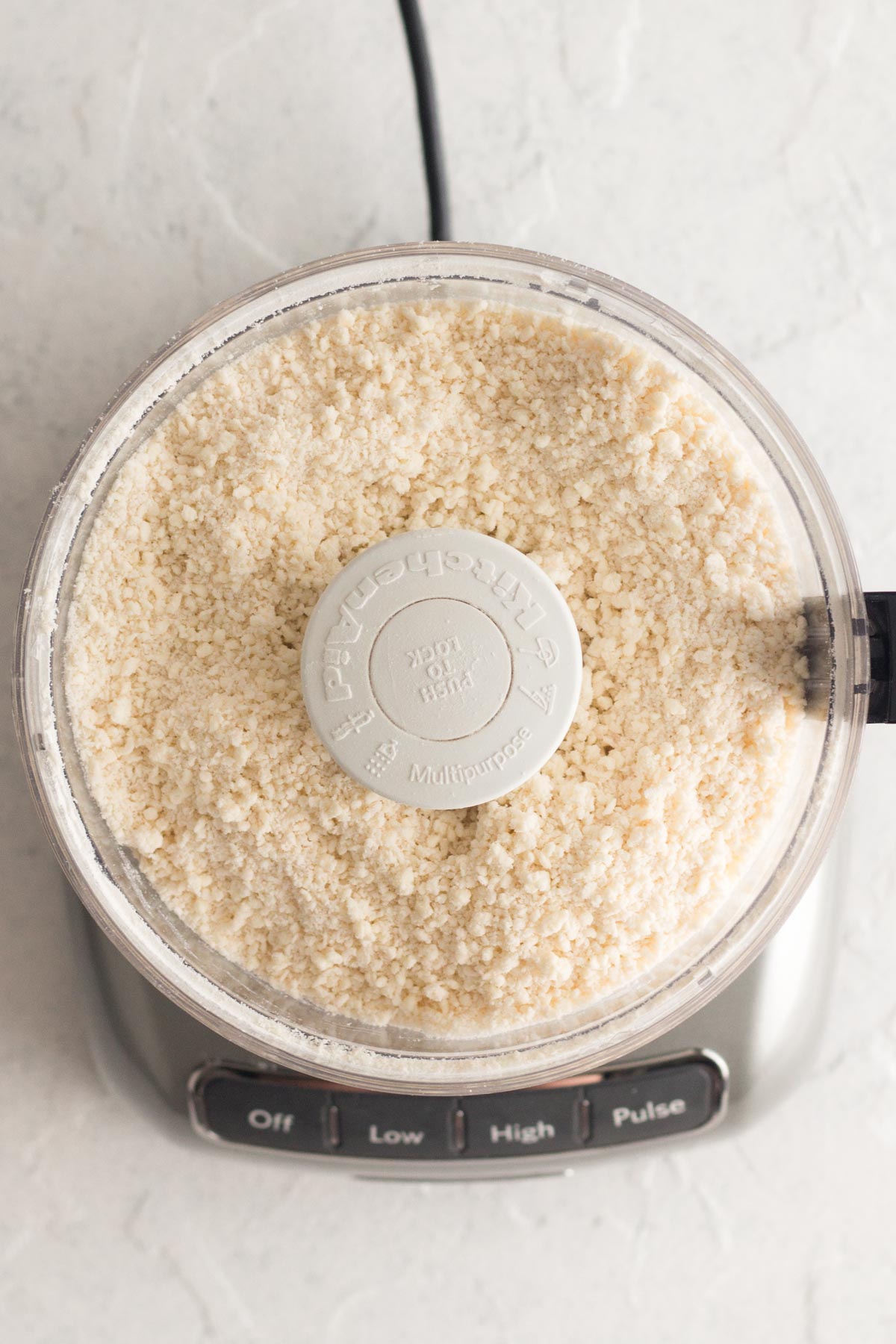 Overhead view of flour mixture and butter blended in food processor.
