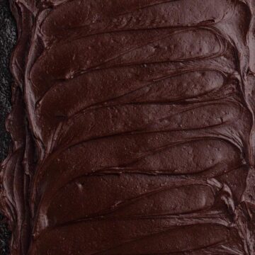 Overhead view of dark chocolate frosting spread on a sheet cake.