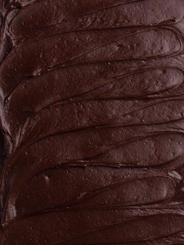 Overhead view of dark chocolate frosting spread on a sheet cake.