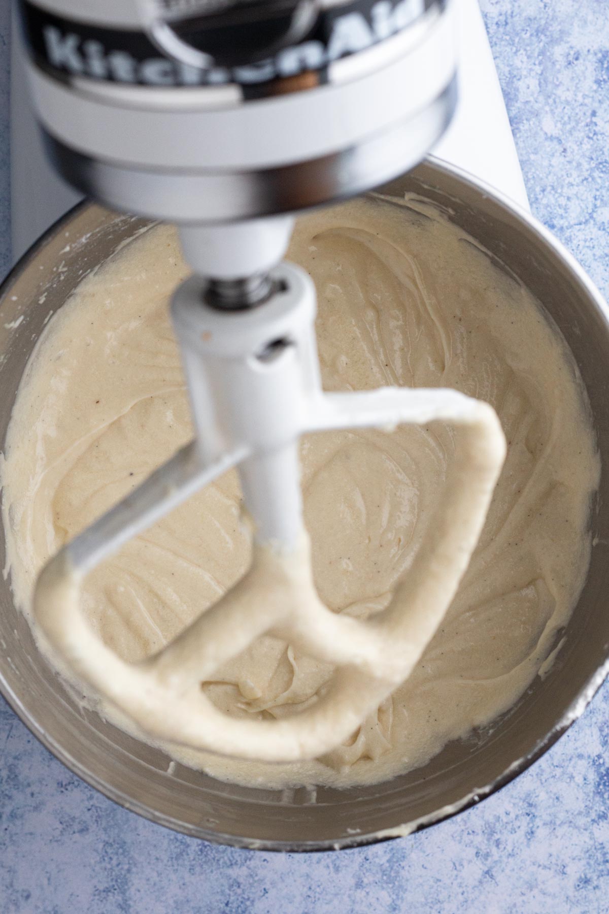 Cake batter in the bowl of a stand mixer with the paddle attachment.