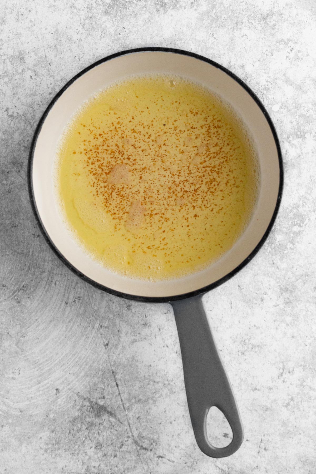 Browned butter in a small pan on a gray surface.