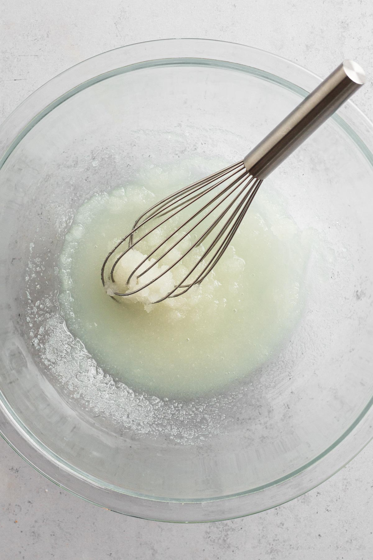 Sugar and oil whisked together in a glass bowl.