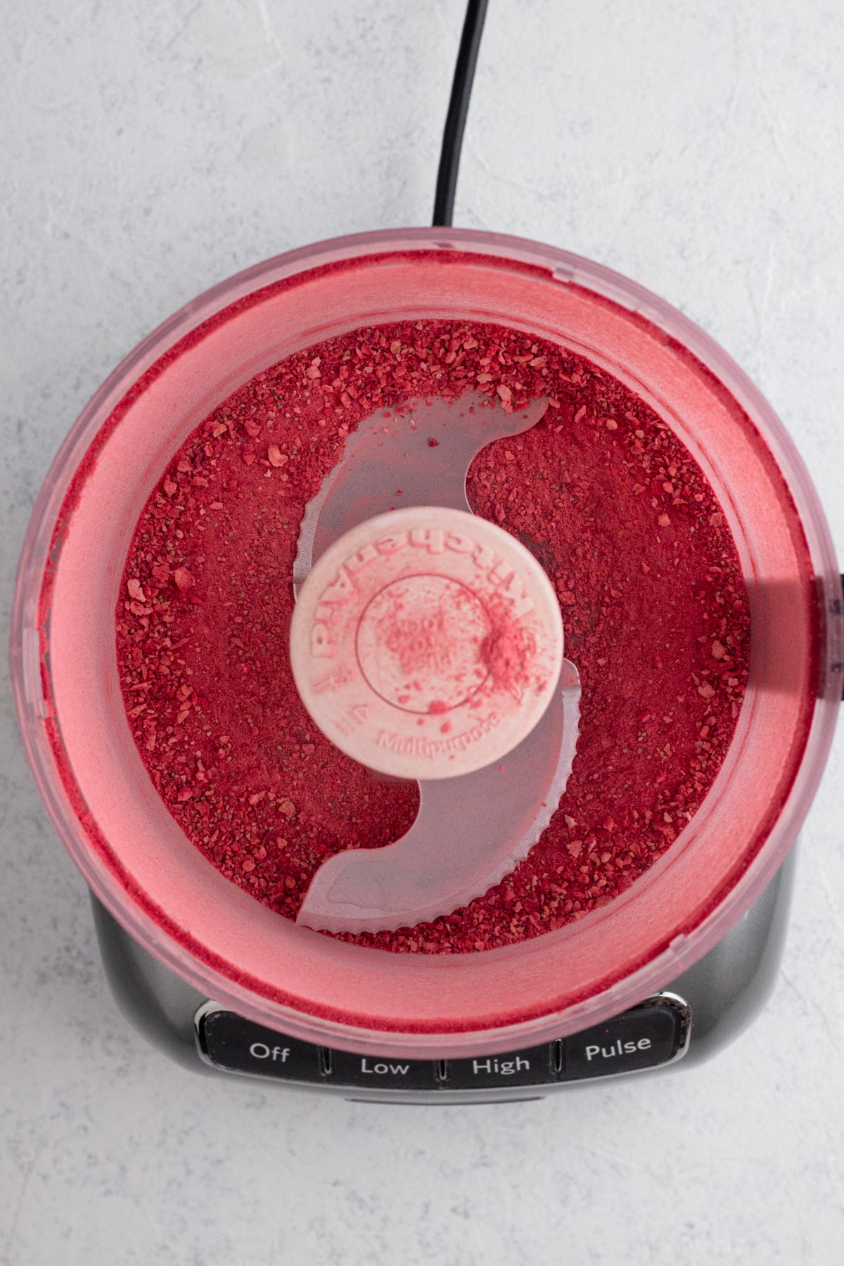 Powdered freeze-dried strawberries in the bowl of a food processor.