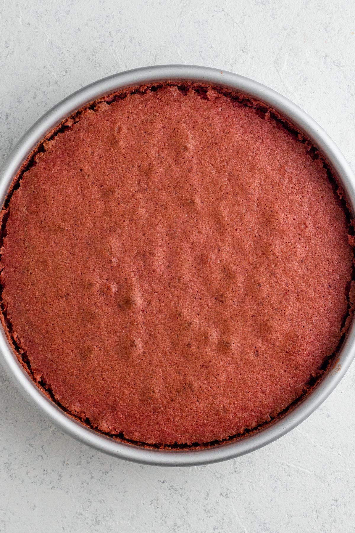 Baked strawberry cake in a round metal pan.