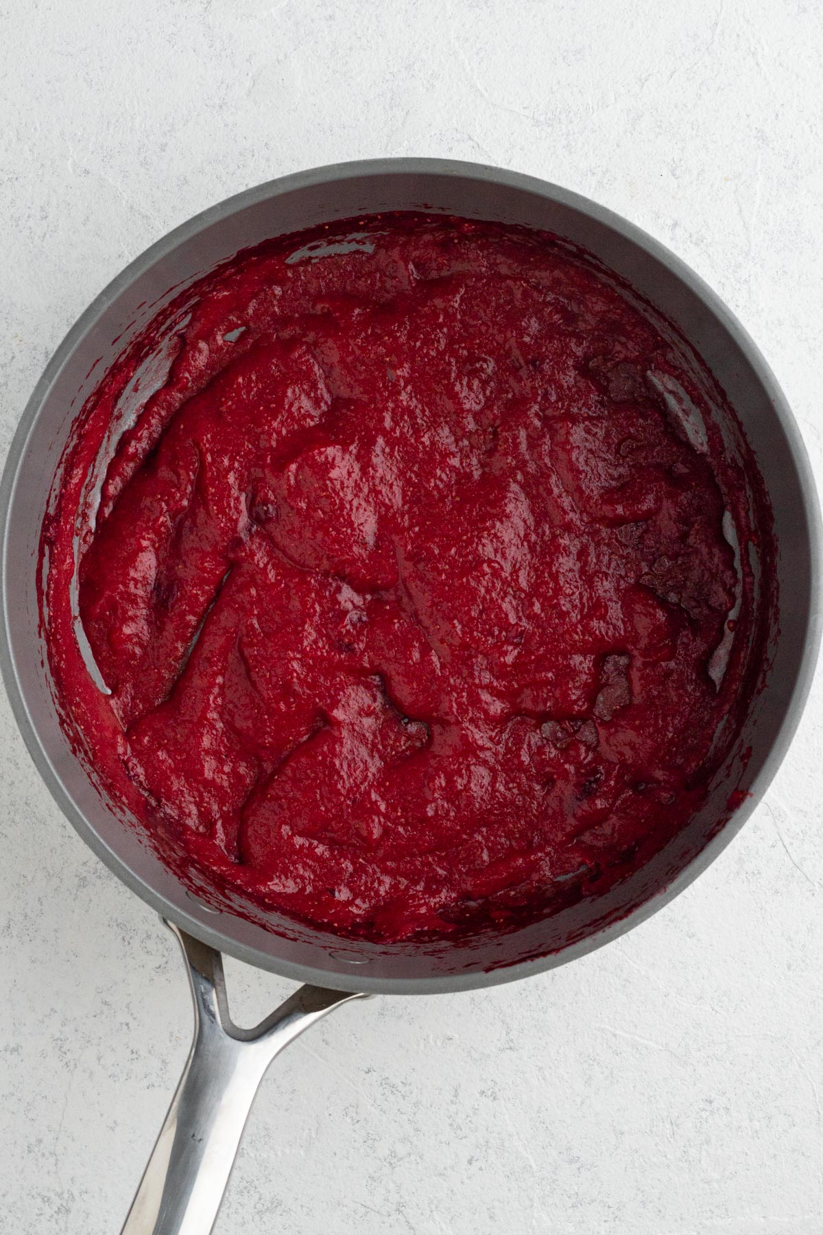 Puréed strawberry cooked down in a pan.