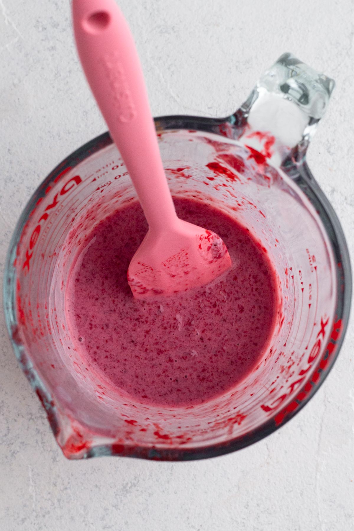 Milk and strawberry purée blended together in a measuring cup.