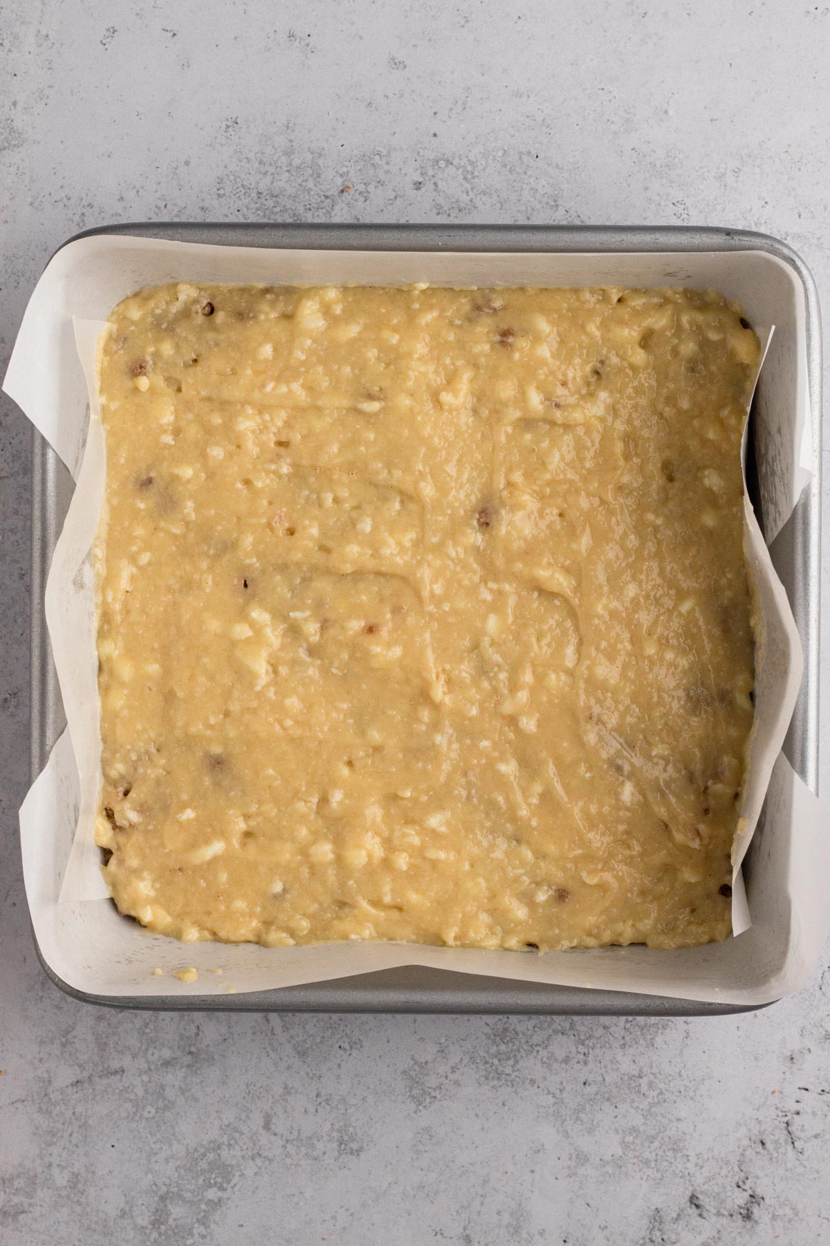Cake batter spread over crumb filling in a square baking pan.