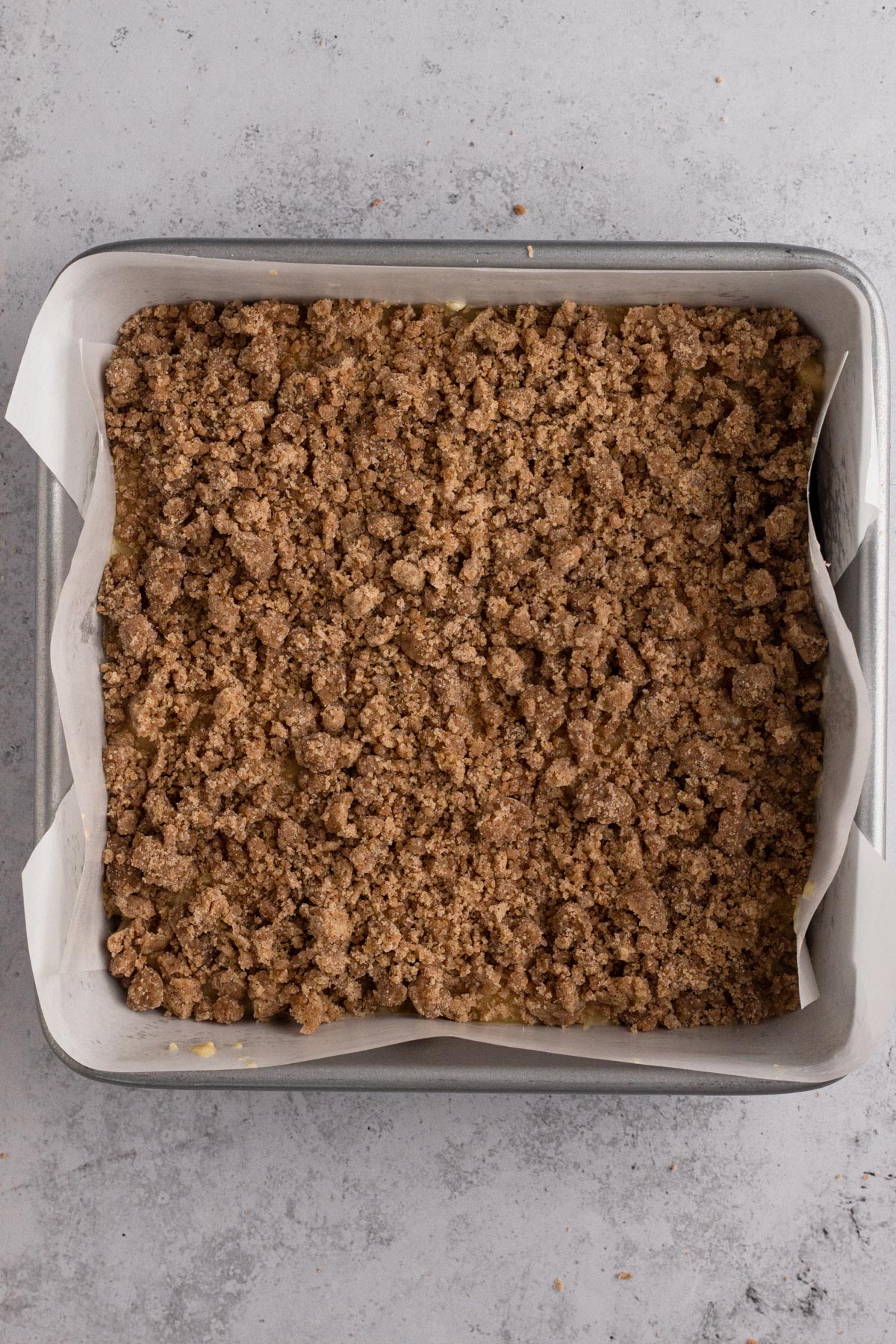 Crumb topping over cake batter in a square baking pan.