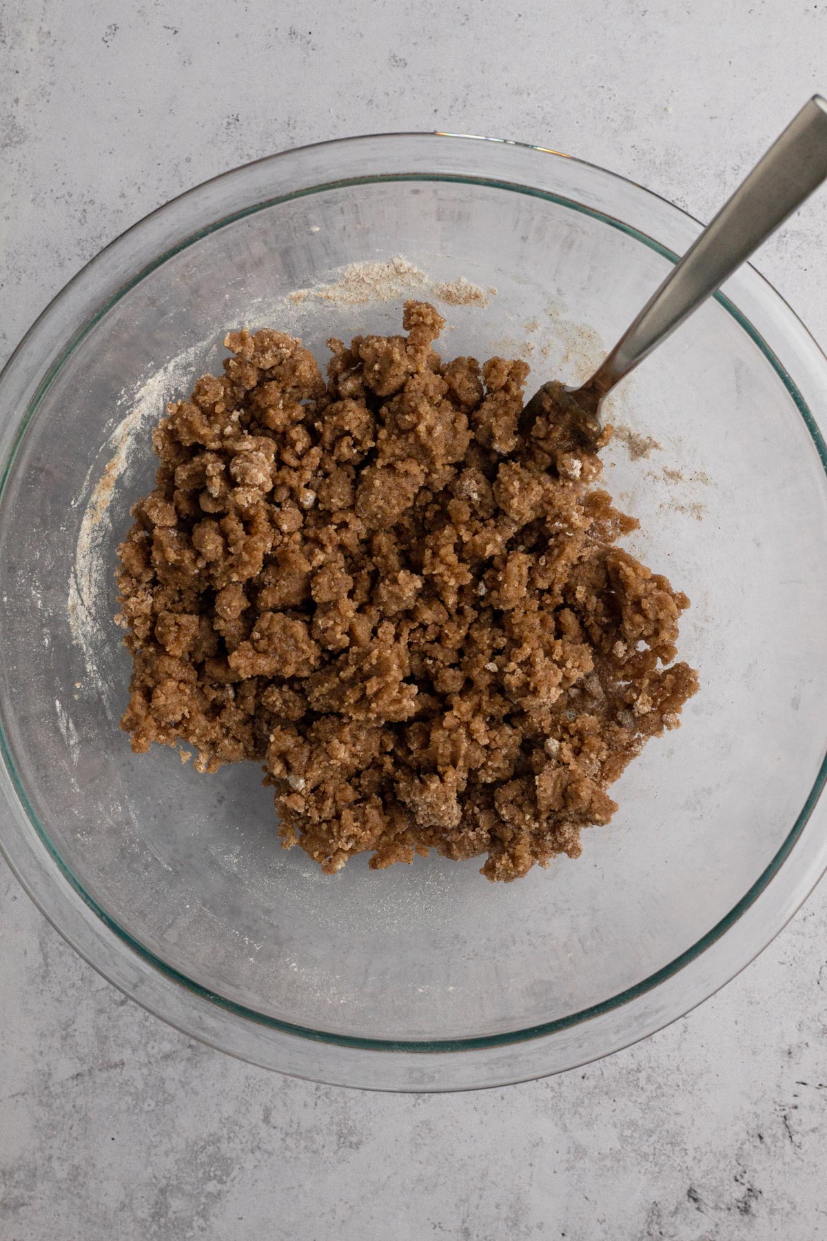 Crumb mixture in a glass mixing bowl with a fork.