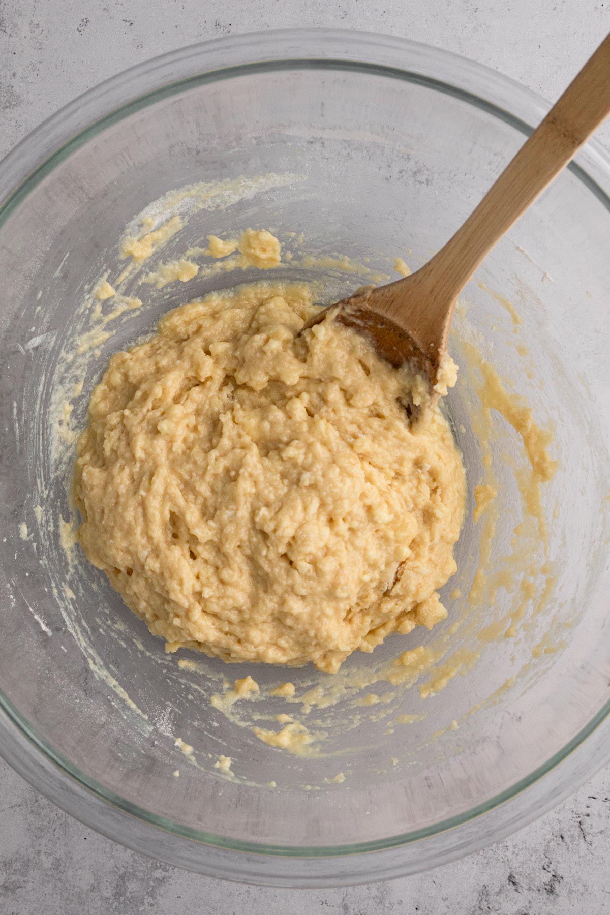 Cake batter in a glass mixing bowl with a wooden spoon.