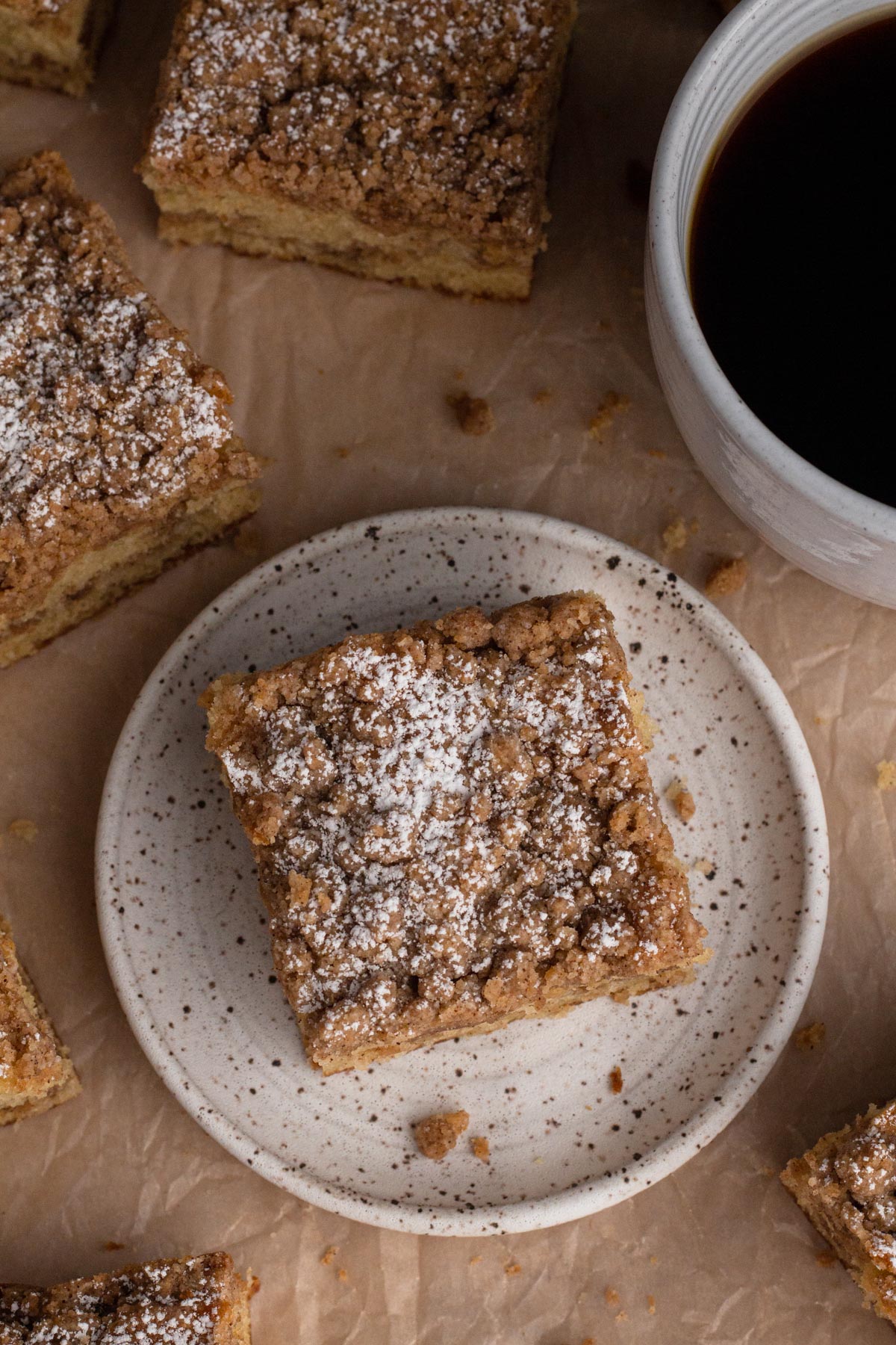 Slices of coffee cake on brown parchment with a mug of coffee.