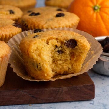 Side view of a bitten muffin on a wooden cutting board.