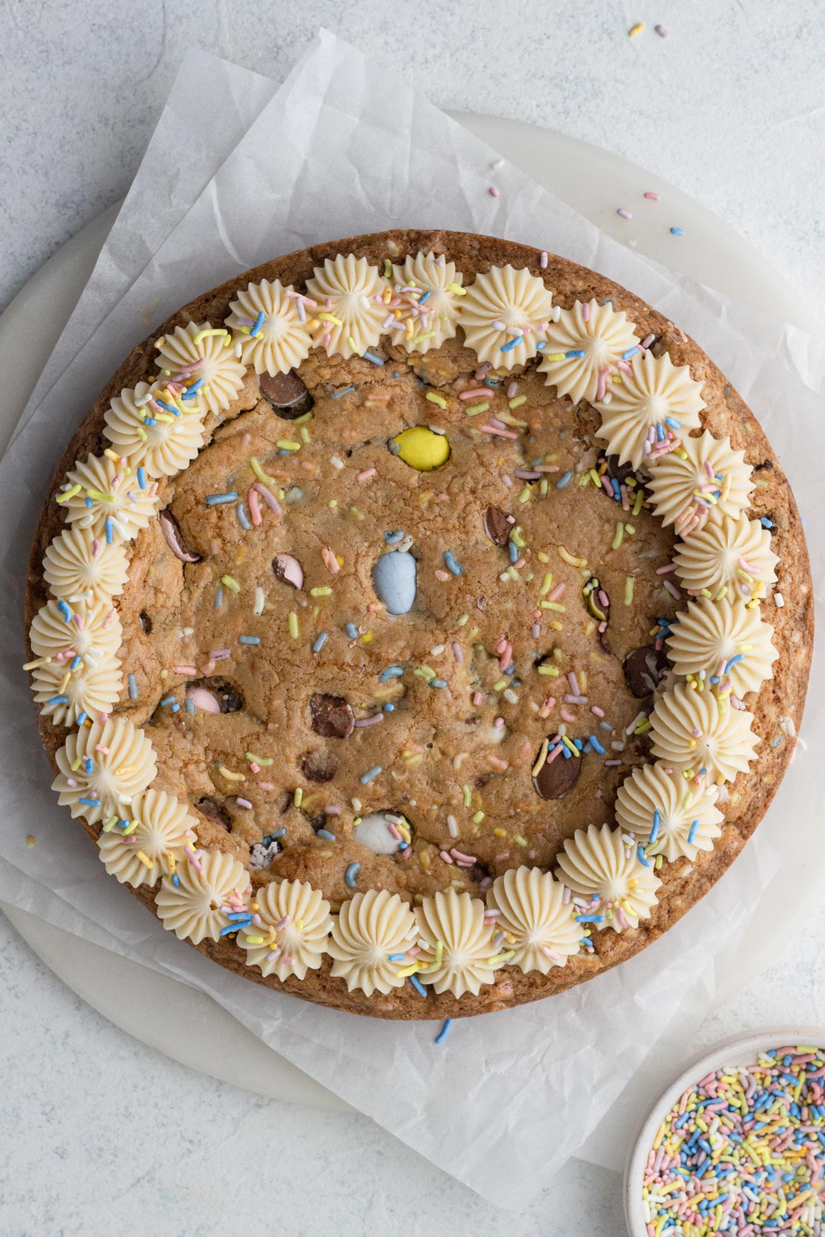 Cookie cake decorated with piped frosting and sprinkles.