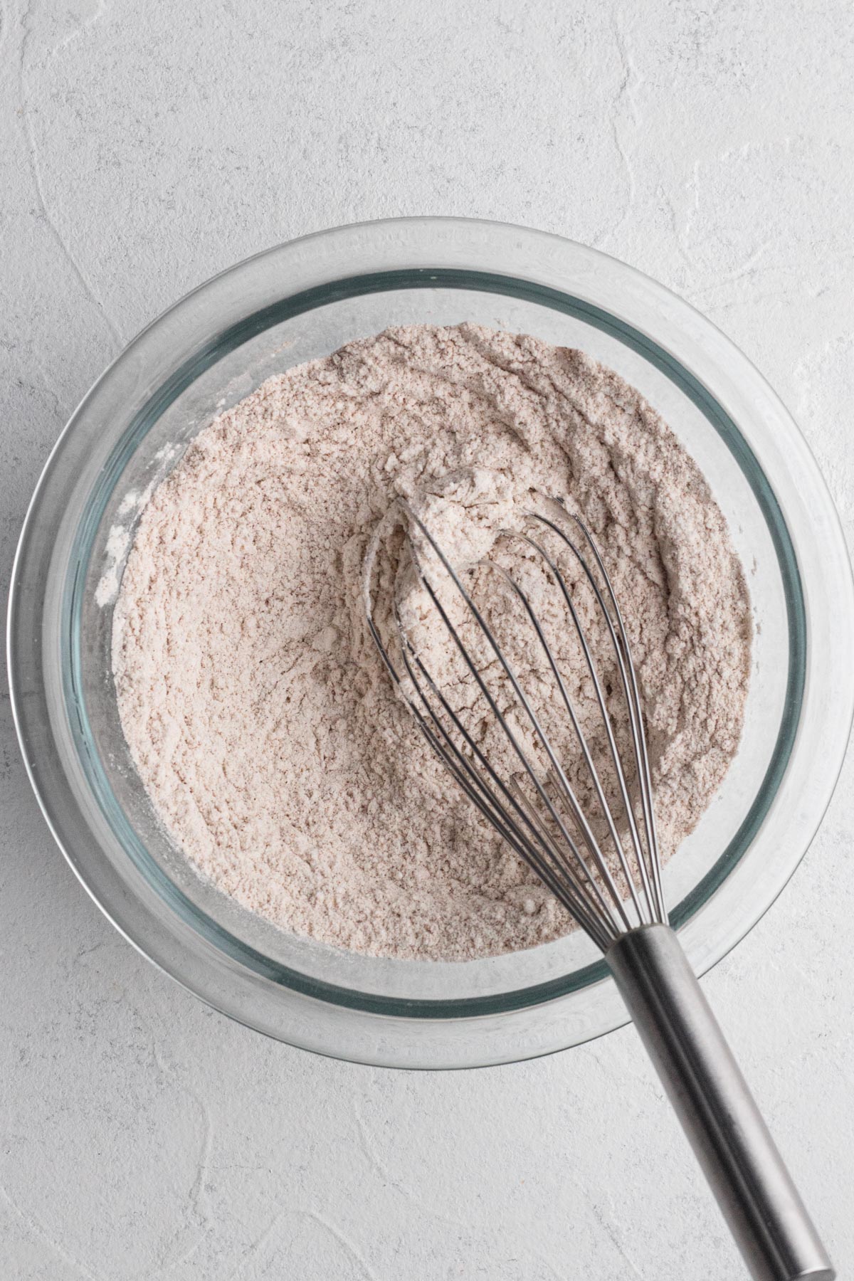 Dry ingredients whisked together in a glass mixing bowl.