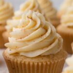 Close-up view of eggnog frosting swirled on the top of a cupcake and sprinkled with ground nutmeg.