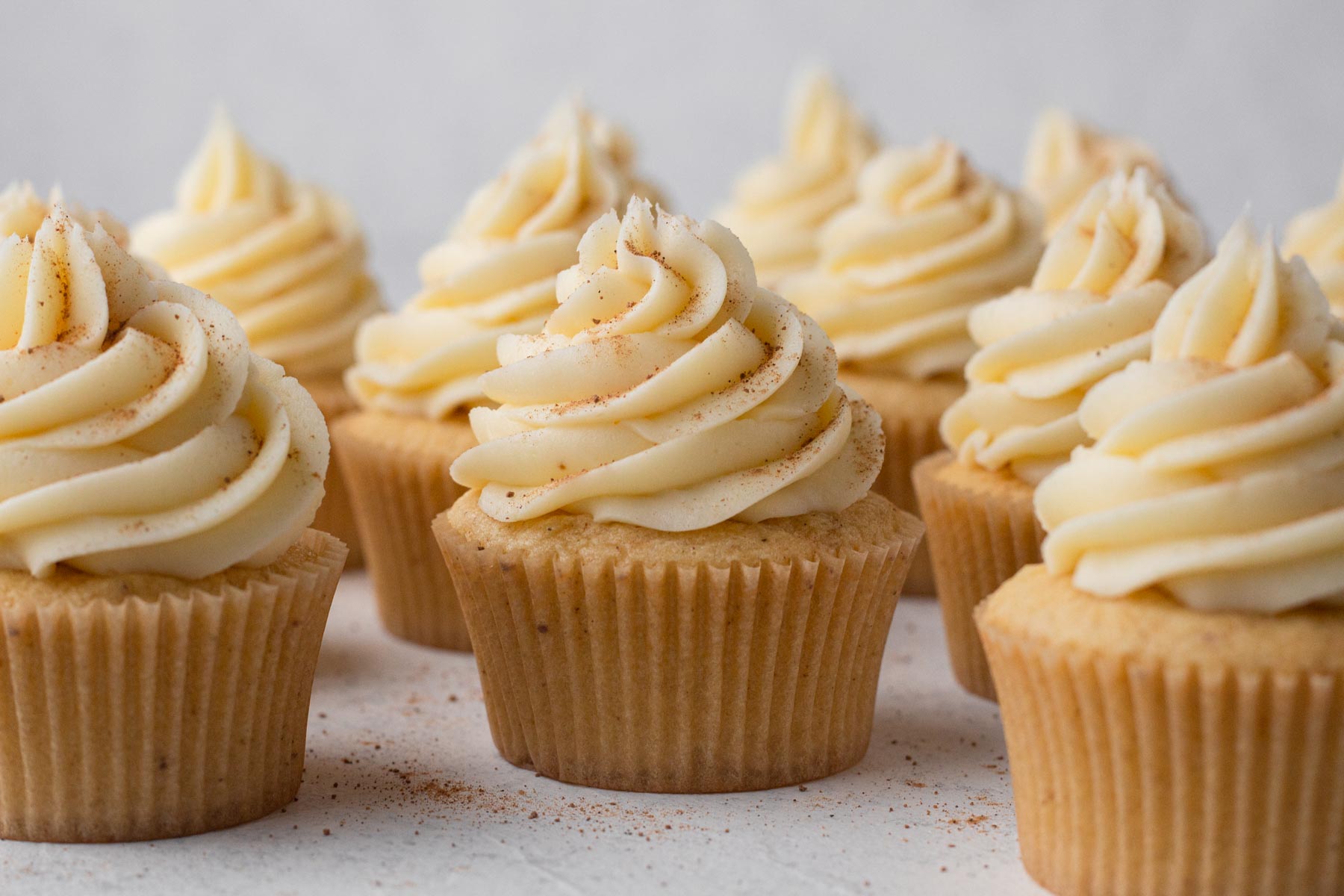 Cupcakes topped with swirls of frosting and a sprinkle of ground nutmeg.