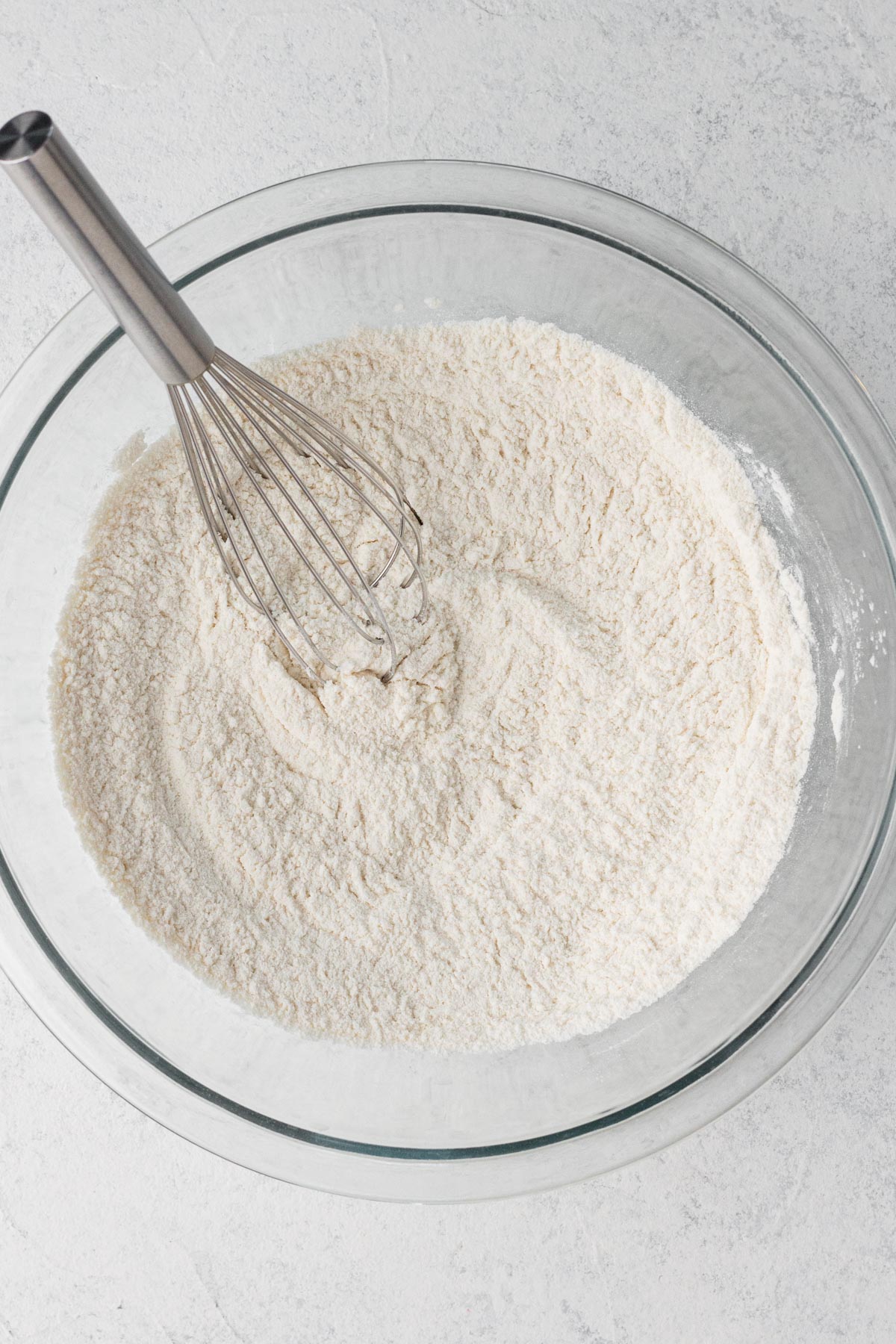 Dry ingredients whisked together in a glass mixing bowl.