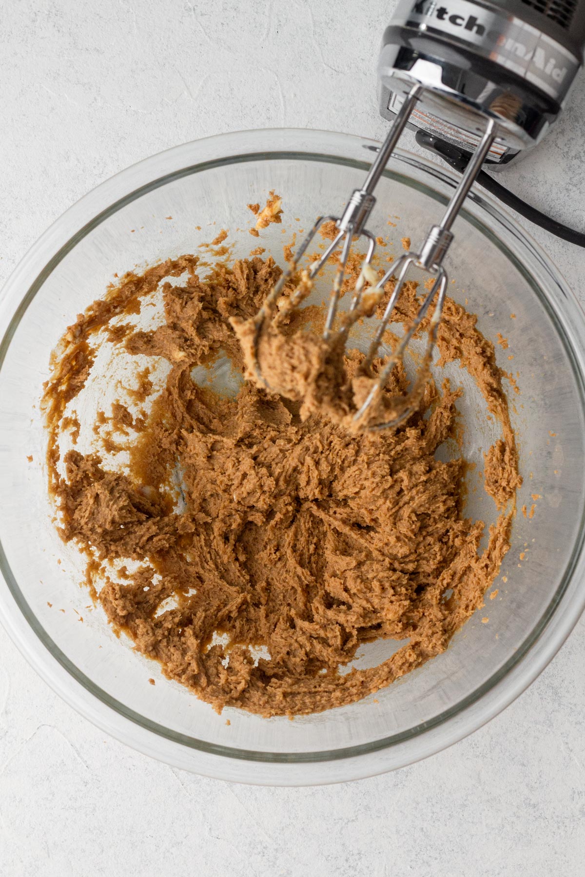 Butter, cookie butter, and sugars beaten together in a glass mixing bowl.
