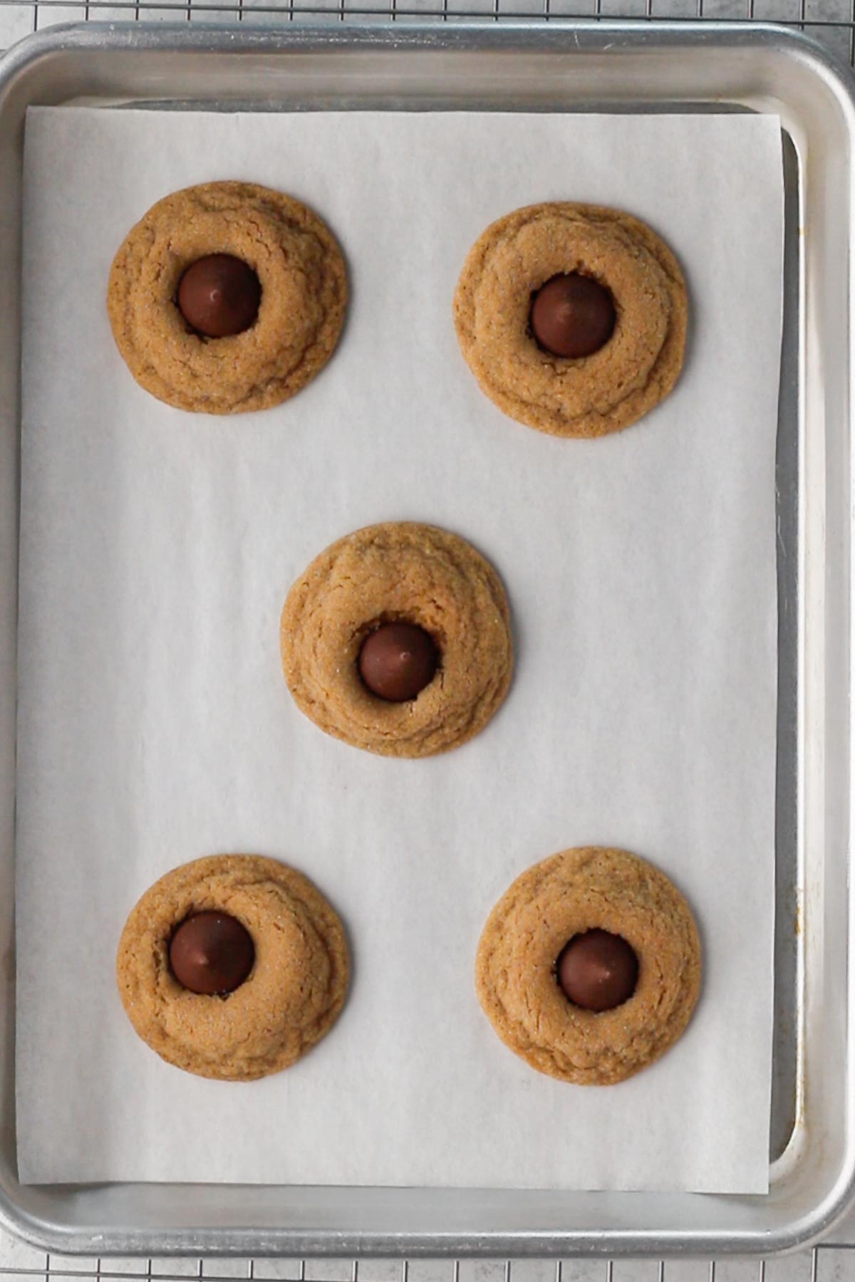 Cookies with Hershey's Kisses on a baking sheet lined with parchment paper.