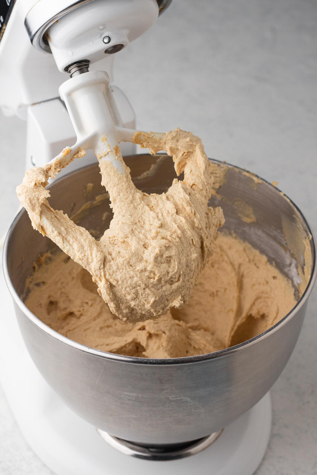 Peanut butter frosting in the bowl of a white stand mixer.