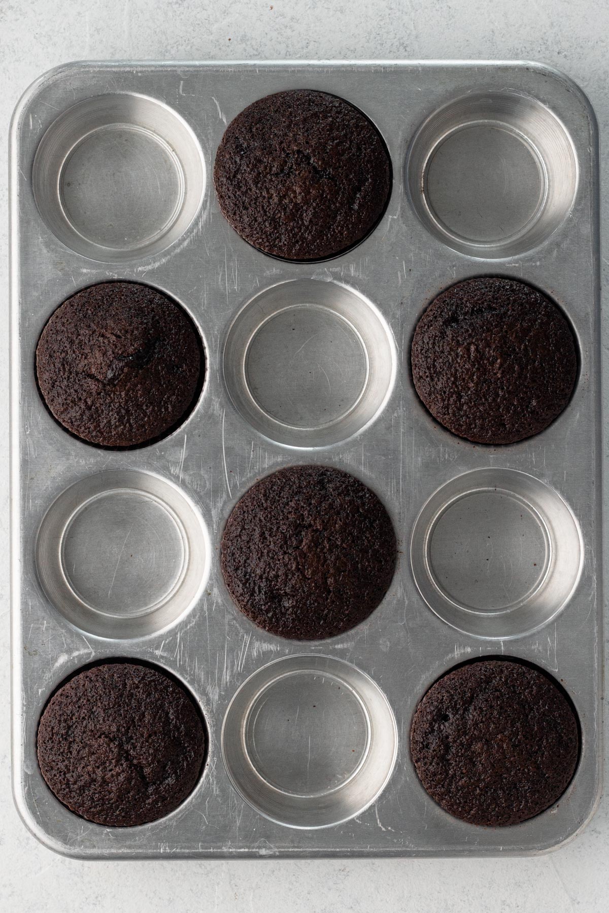 Baked chocolate cupcakes in a metal cupcake pan.