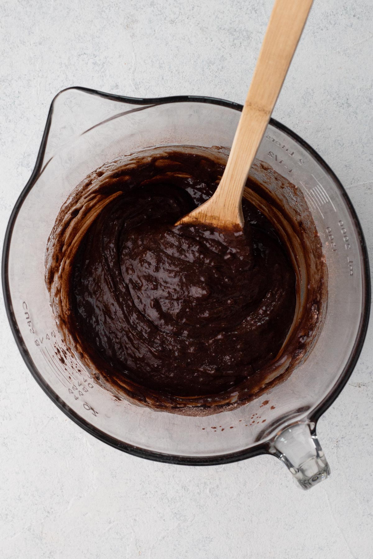 Wet and dry ingredients blended together in a glass batter bowl.