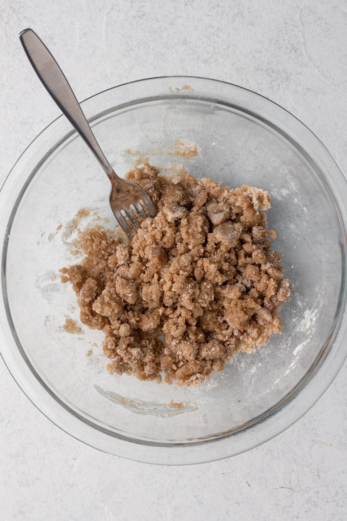 Crumb topping ingredients mixed together in a glass mixing bowl with a fork.
