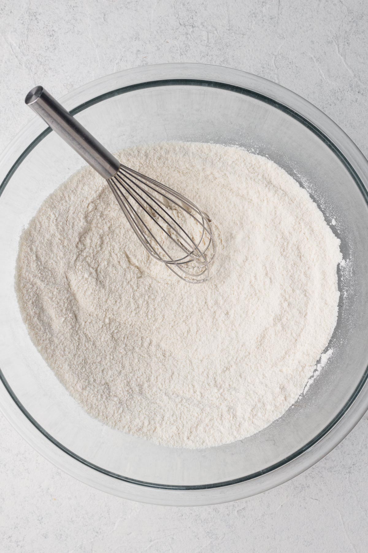 Dry ingredients whisked together in a glass mixing bowl.