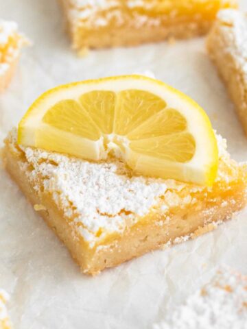 Angled view of a lemon bar with a lemon slice.