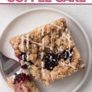 Overhead view of a square slice of coffee cake with blackberries and a drizzle of glaze on a white plate with a text overlay.