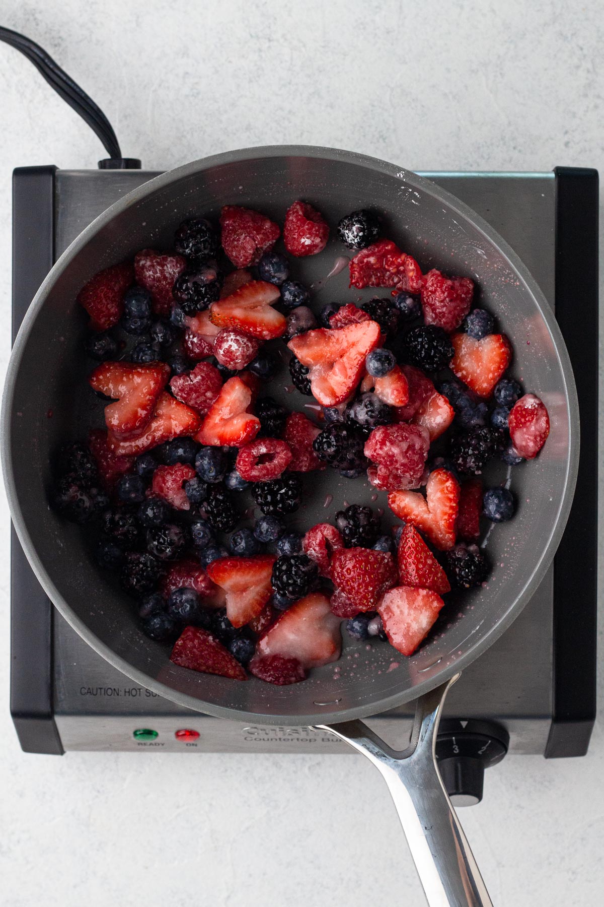 Fruit mixed mixed with filling ingredients in a sauté pan.