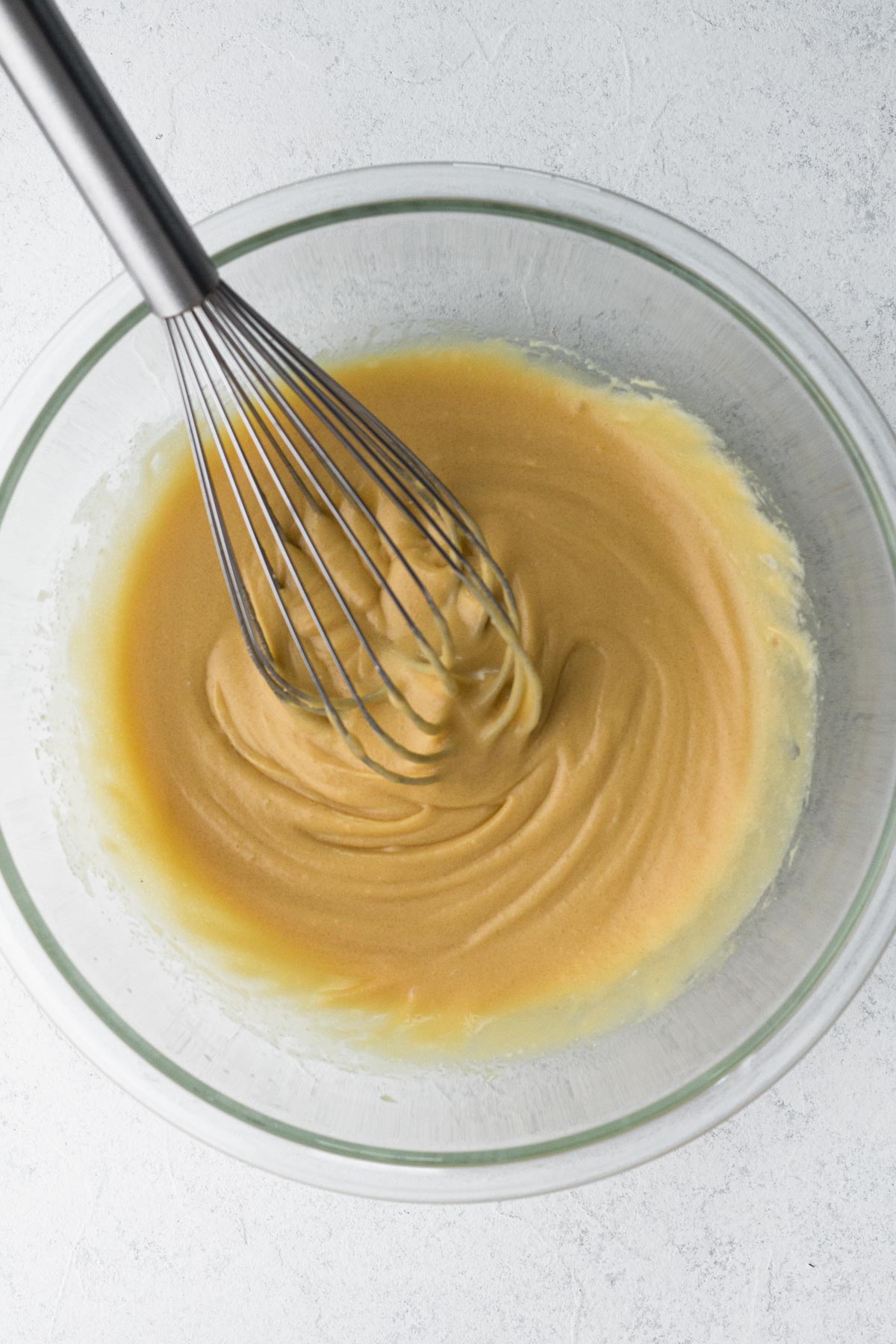 Wet ingredients whisked together in a glass mixing bowl.
