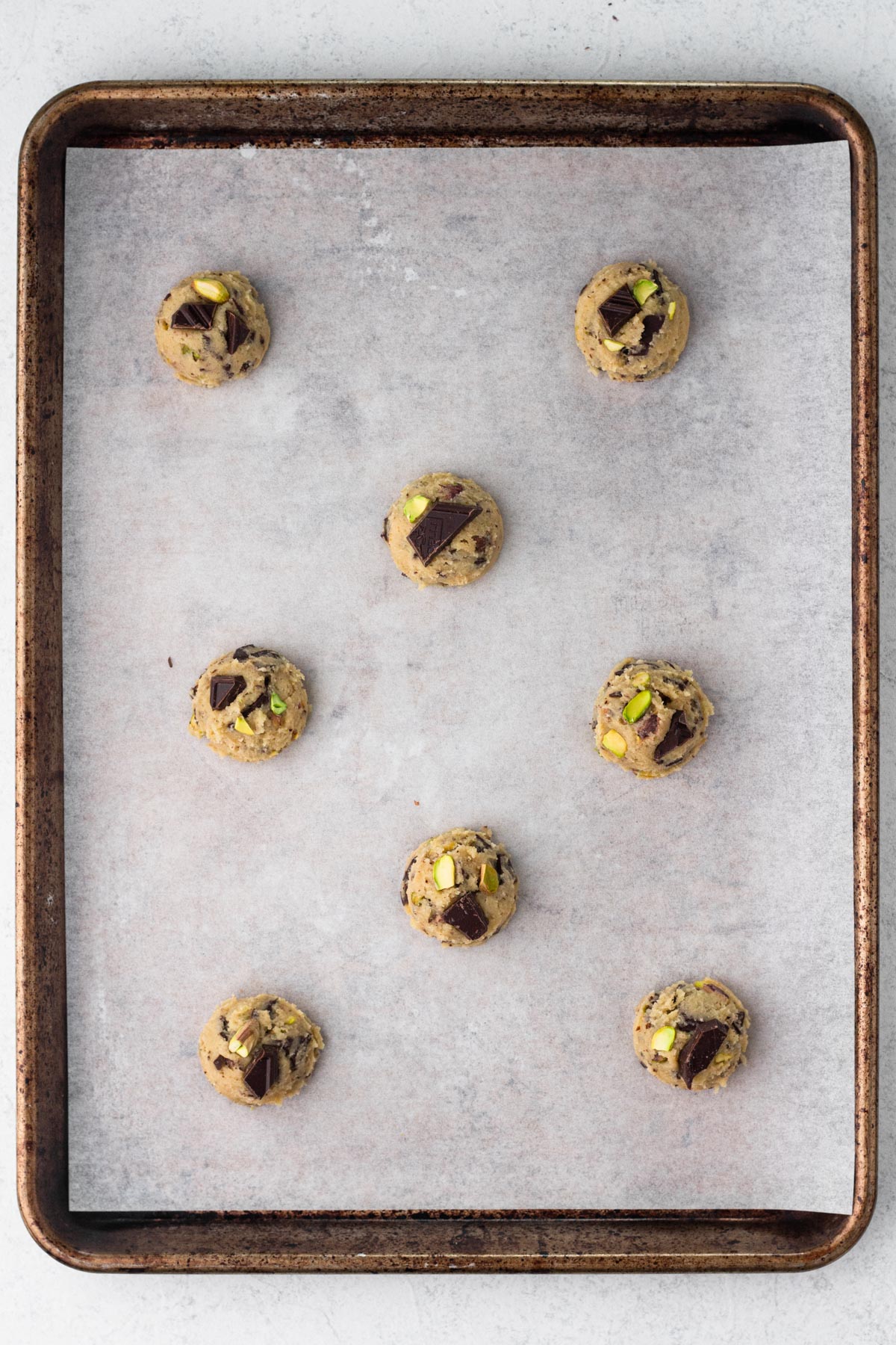Balls of cookie dough on a baking sheet lined with parchment paper.