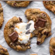 Two halves of a s'mores cookie with a marshmallow pull with a text overlay.