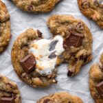 Two halves of a s'mores cookie with a marshmallow pull and melty chocolate.