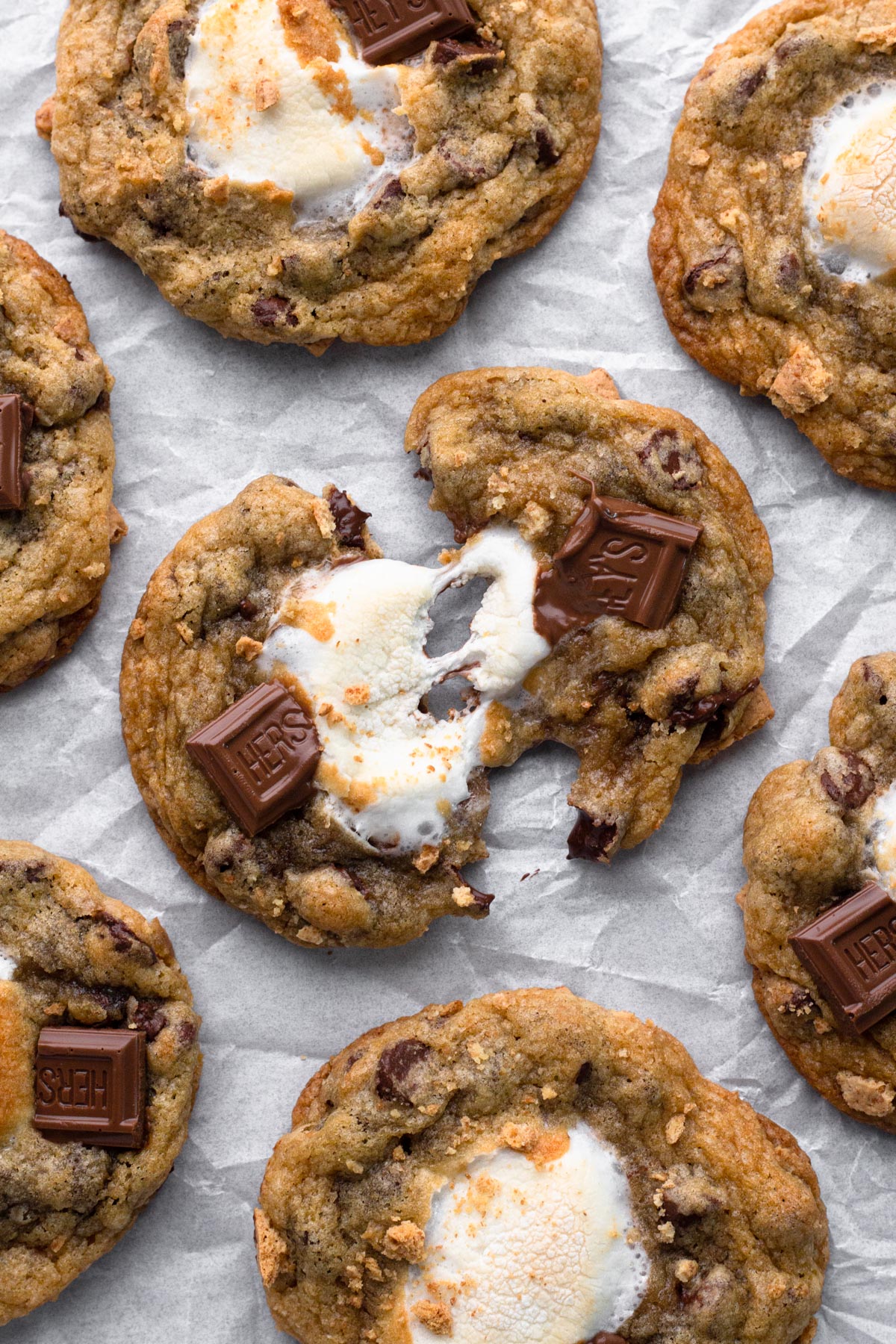Two halves of a s'mores cookie with a marshmallow pull and melty chocolate.